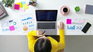 Automação de marketing - Jovem analisando dados no computador com a mesa cheia de gráficos